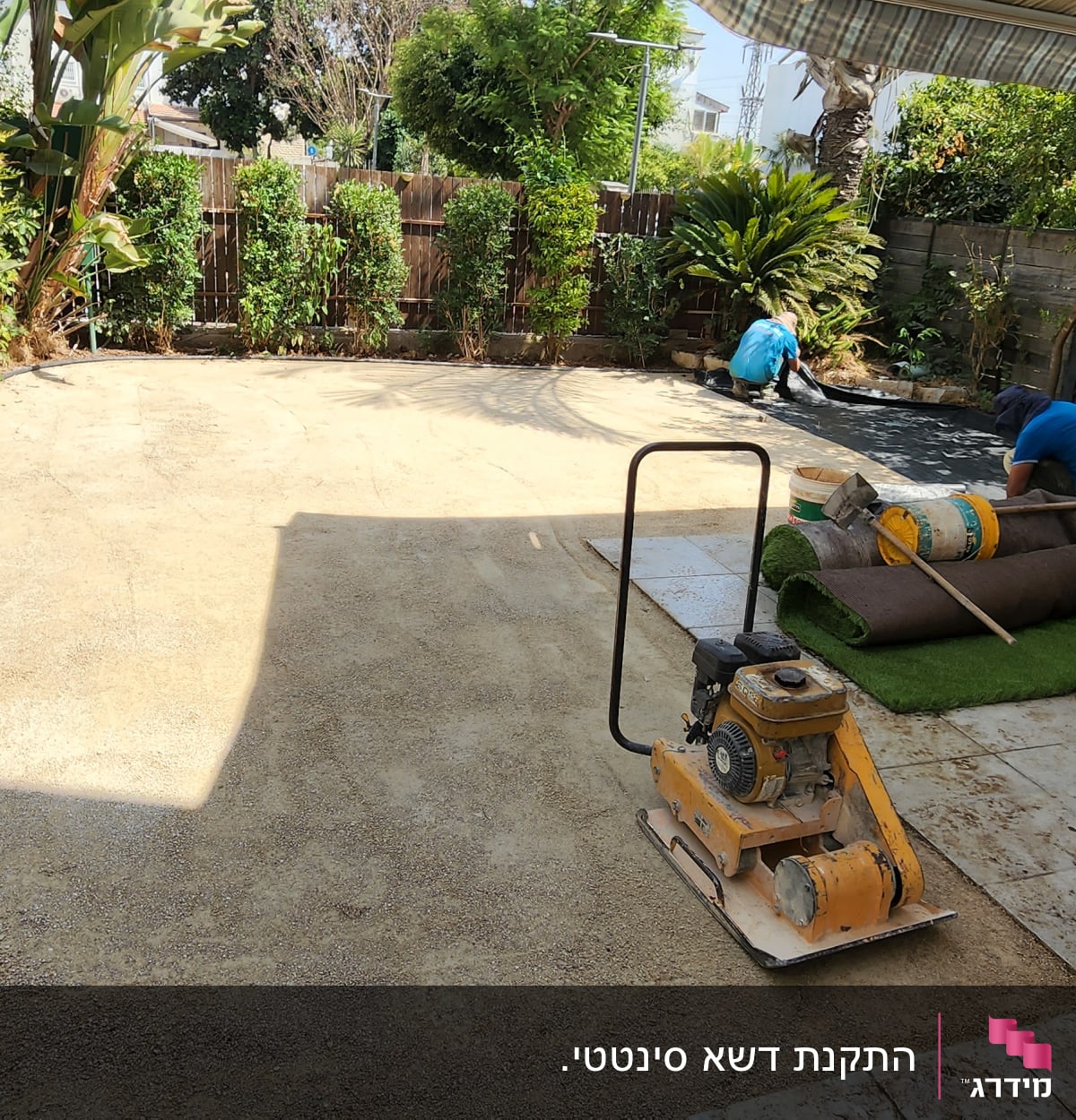 עובדים מתקינים דשא סינתטי בחצר עם כלים וחומרים